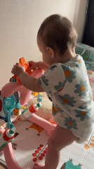 Baby plays with activity center in white floral onesie
