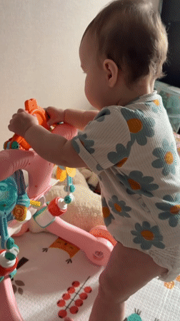 Baby plays with activity center in white floral onesie
