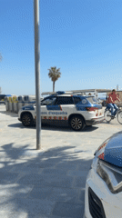Police van stationed at busy Barcelona beach during sunny day