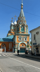 Pedestrian crosses street near colorful Moscow church