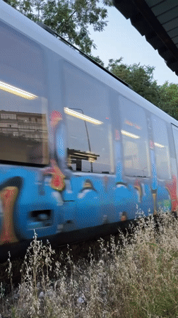 Graffiti-tagged passenger train passing through Lovech, Bulgaria