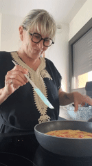 Woman cooks tomato omelet in French kitchen