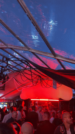 Festive indoor crowd under a lit transparent tent in Düsseldorf