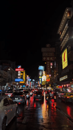 Neon-lit Bangkok street traffic on a wet night