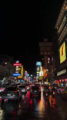 Neon-lit Bangkok street traffic on a wet night