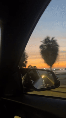 Driver films side mirror showing white car behind in Arica