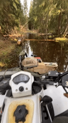 ATV with chainsaw crosses muddy water in Russian forest