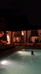 Nighttime swimming captured at illuminated Mengwi resort poolside