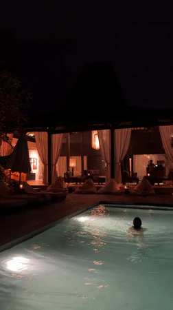 Nighttime swimming captured at illuminated Mengwi resort poolside