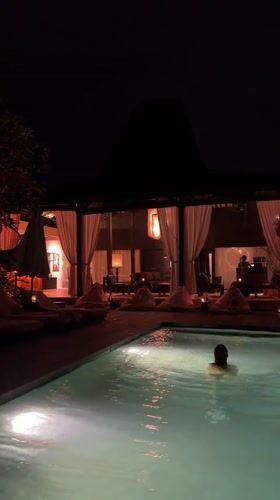 Nighttime swimming captured at illuminated Mengwi resort poolside