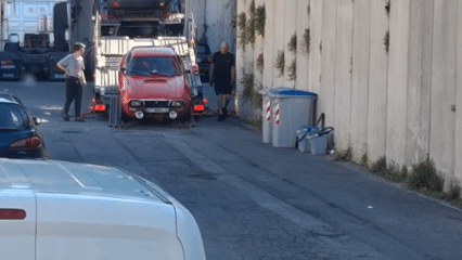 Vintage rally car unloaded from carrier truck in Savona