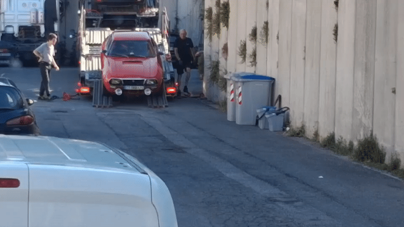 Vintage rally car unloaded from carrier truck in Savona