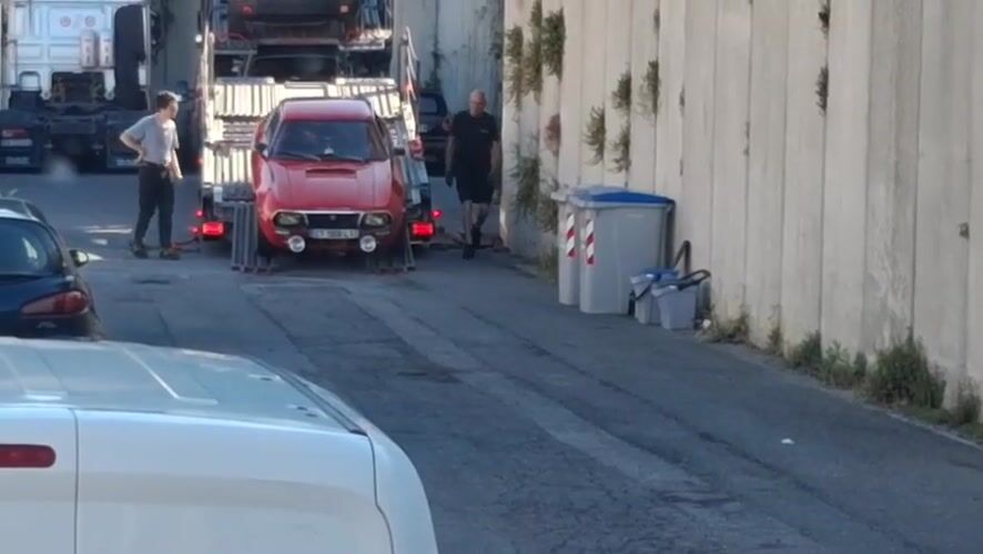 Vintage rally car unloaded from carrier truck in Savona