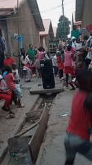 Children dance in residential alley with portable speaker