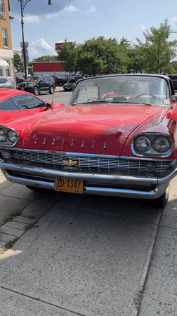 Classic red Chrysler convertible parked on a New York sidewalk