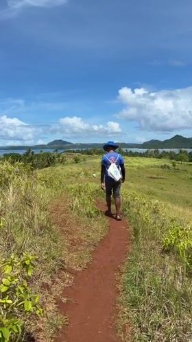 Man walks dirt path through fields in Dapa, Philippines
