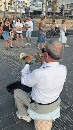 Trumpet player and Argentina crew on Tel Aviv's beachfront promenade