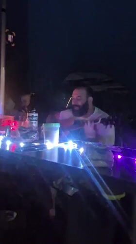 Acoustic guitar and drinks at a colorful late-night outdoor gathering