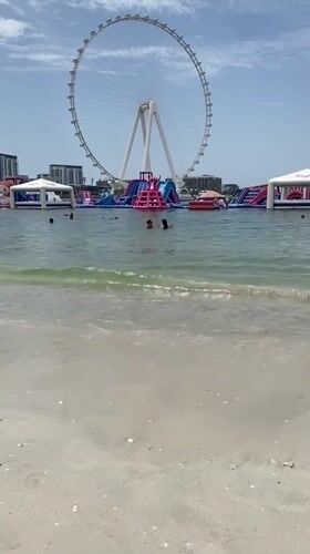 Beach swimmers enjoy clear waters in Dubai morning scene