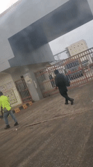 Two people run toward industrial facility in Gwagwada, Nigeria