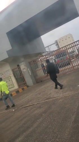 Two people run toward industrial facility in Gwagwada, Nigeria