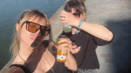Two women share drinks by canal in Pantin