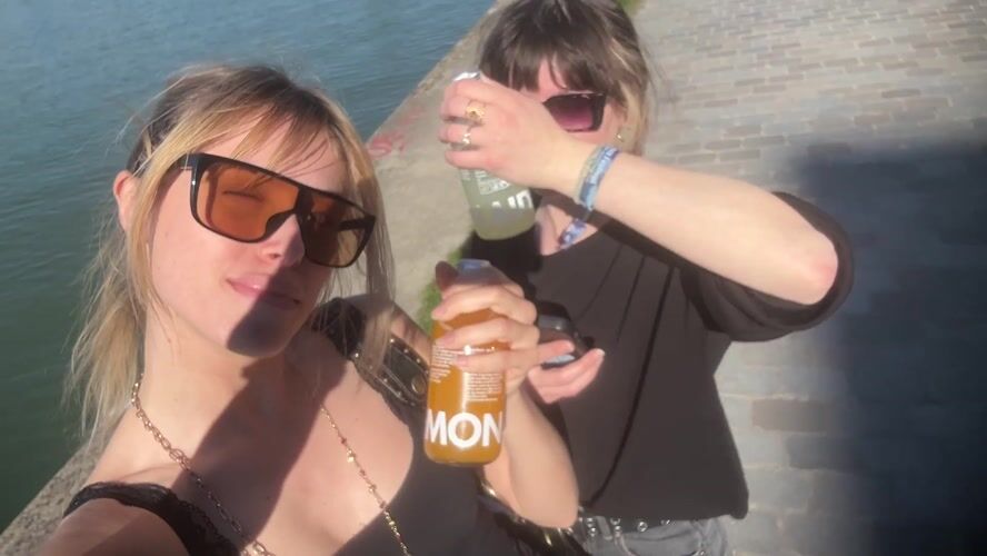 Two women share drinks by canal in Pantin