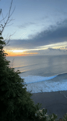 Woman watches dramatic sunset from Indonesian clifftop overlook