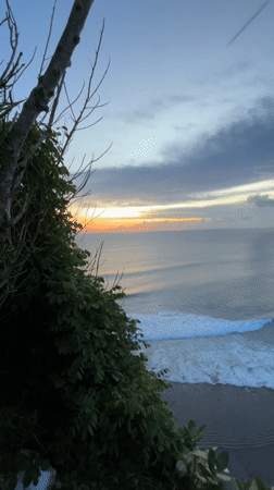 Woman watches dramatic sunset from Indonesian clifftop overlook