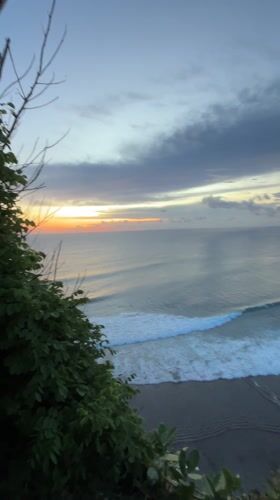 Woman watches dramatic sunset from Indonesian clifftop overlook