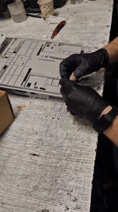 Gray plastic device being carefully disassembled with gloved hands
