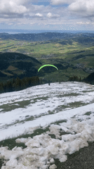 Paraglider spotted descending over Swiss mountain landscape near Schwende-Rüte