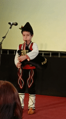 Young boy performs bagpipes in traditional costume in Bulgaria