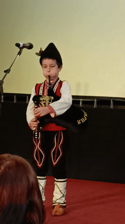 Young boy performs bagpipes in traditional costume in Bulgaria