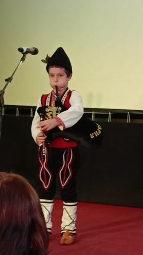 Young boy performs bagpipes in traditional costume in Bulgaria