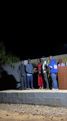 Nighttime community speaking event held on outdoor stage in Durimi