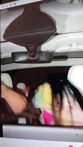 This media file appears to be a dashcam recording from inside a vehicle, capturing a tense interaction between two individuals. The subjects are a young man and a young woman, both visible in the car's interior. The man is on the left, his face partially obscured, with dark, curly hair. The woman is on the right, with long, dark hair and wearing a brightly colored, possibly tie-dye, garment.

The setting is the interior of a car, with the rearview mirror prominently displayed on the windshield. The lighting suggests it is daytime, though the interior of the car is dark. The focus of the interaction seems to be an altercation, as the woman is seen pushing or hitting the man's arm away with force. The man appears to be reacting with a mixture of surprise and exasperation, as indicated by his facial expression and hand gestures. The overall emotion conveyed is one of conflict and distress.

No visible text is present in the video frames. The location context of Krasivka, Ukraine, does not provide any additional visual cues within the media itself. The activity is a clear interpersonal dispute occurring within the confines of a vehicle.