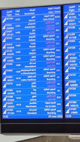 The video shows a close-up, slightly shaky, view of multiple large, blue digital departure boards at an airport. The boards display flight information in Arabic and English, including flight numbers, destinations, times, and gate statuses. The information changes as the camera pans across the screens. The dominant colors are blue and white. The environment appears to be indoors, likely an airport terminal. The date "29 June 2026" is visible on the bottom of one of the boards.
