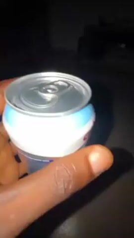 A dark-skinned hand holds a can of Chivita Mixed Fruit Drink Sparkling in a dimly lit environment. The can is light blue and white with images of assorted fruits. The hand rotates the can to display different sides. A couch can be seen in the background.