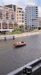 Two passengers cruise Alkmaar canal in wooden motorboat