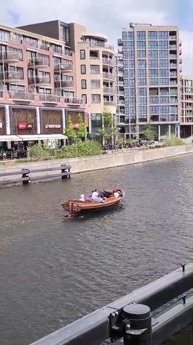 Two passengers cruise Alkmaar canal in wooden motorboat
