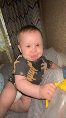 Baby plays with bottle on bed during afternoon