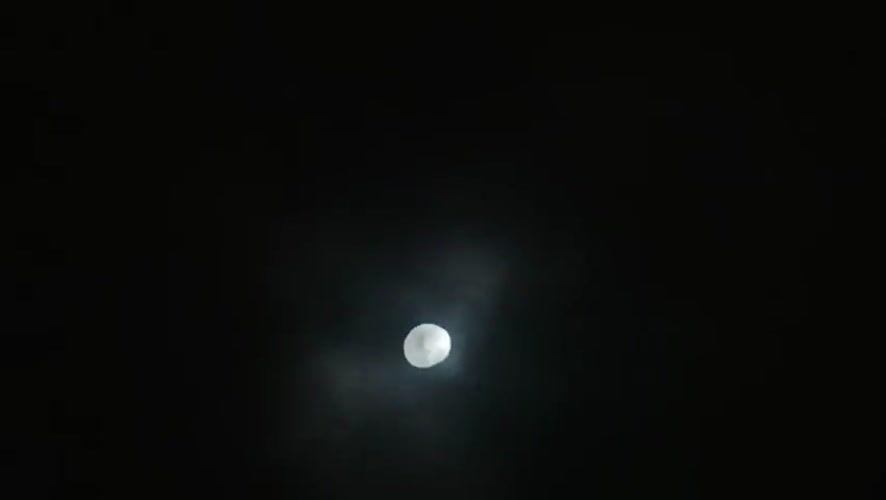 Gibbous moon observed through cloudy night sky in Porlamar