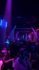 Nightclub patrons dance under colorful lights during evening festivities