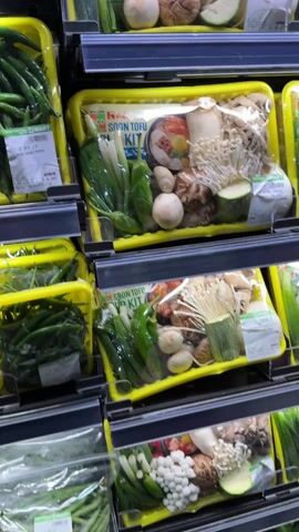 The video shows a shelf in a grocery store that is stocked with various vegetable packages. The packages are arranged neatly and the shelves are well lit. A hand reaches towards a yellow package labeled “House Foods Soon Tofu Soup Kit”. The package contains several vegetables, including green onions, peppers, mushrooms, and zucchini. The video then focuses on the Soon Tofu Soup Kit.