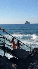 Swimmers gather at a rocky Palermo seaside platform