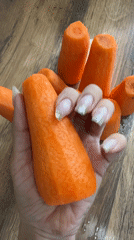 Person with glittery manicure handles fresh carrots in Russia
