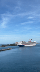 Carnival cruise ship enters harbor past lighthouse and breakwaters