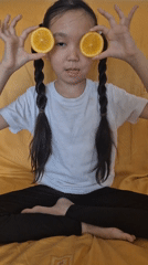 Girl enjoys orange snack on bed in Kokshetau