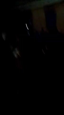 The video is dark and blurry. It appears to show a group of people gathered outdoors at night. A single light source is visible at times. There is movement and indistinct shapes suggesting people and objects. The video appears to have been taken from a moving or unsteady position.